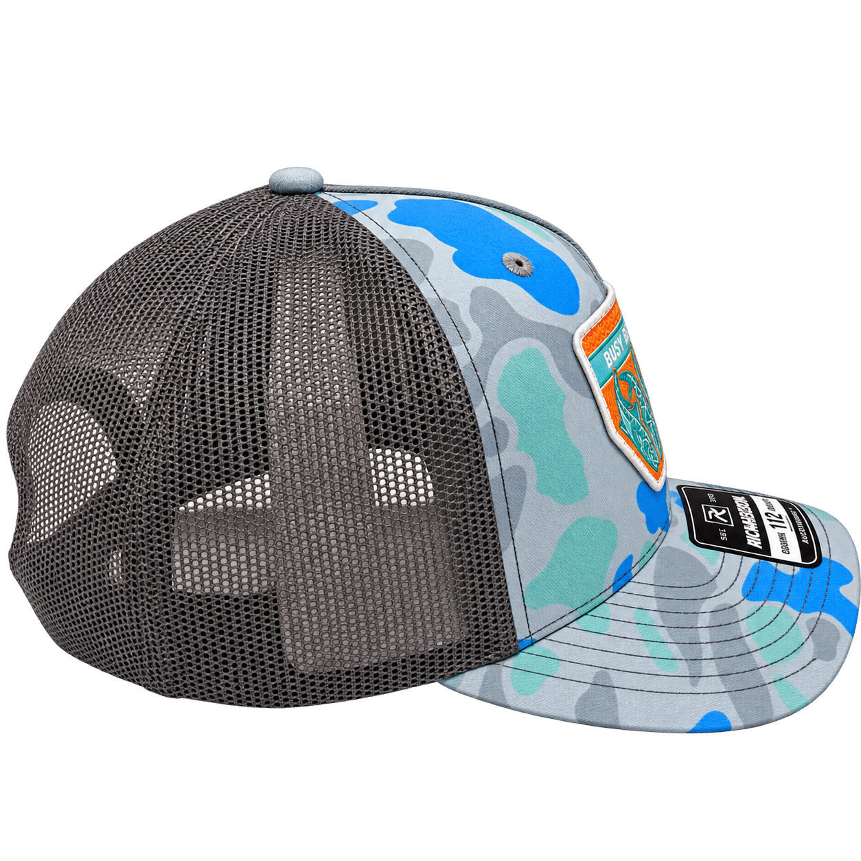 Side view of Busy Bee Outdoors Richardson 112 trucker hat featuring blue, aqua and gray camouflage, charcoal mesh back and curved bill.