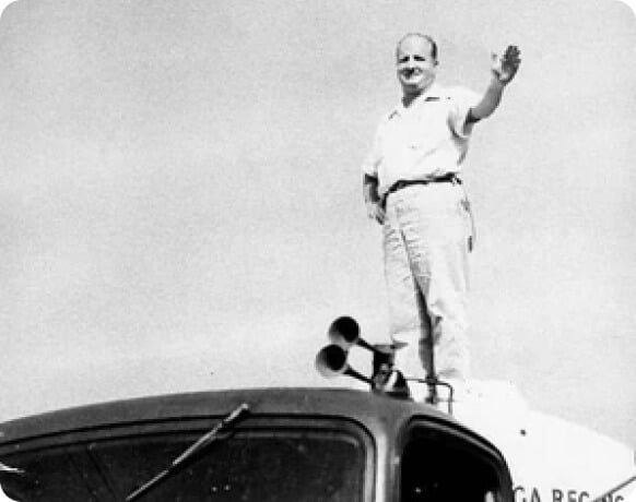 Kin Johnson waving to camera while standing on top of truck